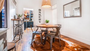 A dining area with a round wooden table, metal chairs, a hanging light fixture, and a cowhide rug.