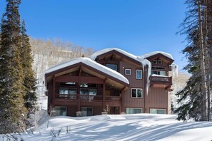 Un chalet à étages, doté d’une façade en bois, de grandes fenêtres et de balcons.