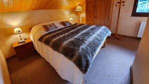 Un dormitorio con cama, mesita de noche con lámpara, armario de madera y suelo de madera.