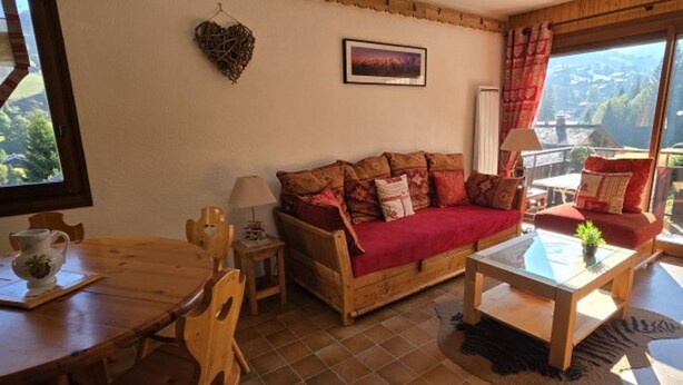 Una sala de estar acogedora con un sofá de madera, una mesa de comedor y vistas al exterior.