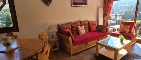 Una sala de estar acogedora con un sofá de madera, una mesa de comedor y vistas al exterior.