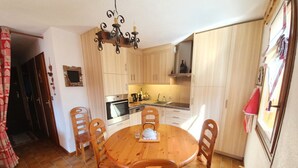 Una cocina compacta con una mesa redonda de madera, cuatro sillas y electrodomésticos básicos.