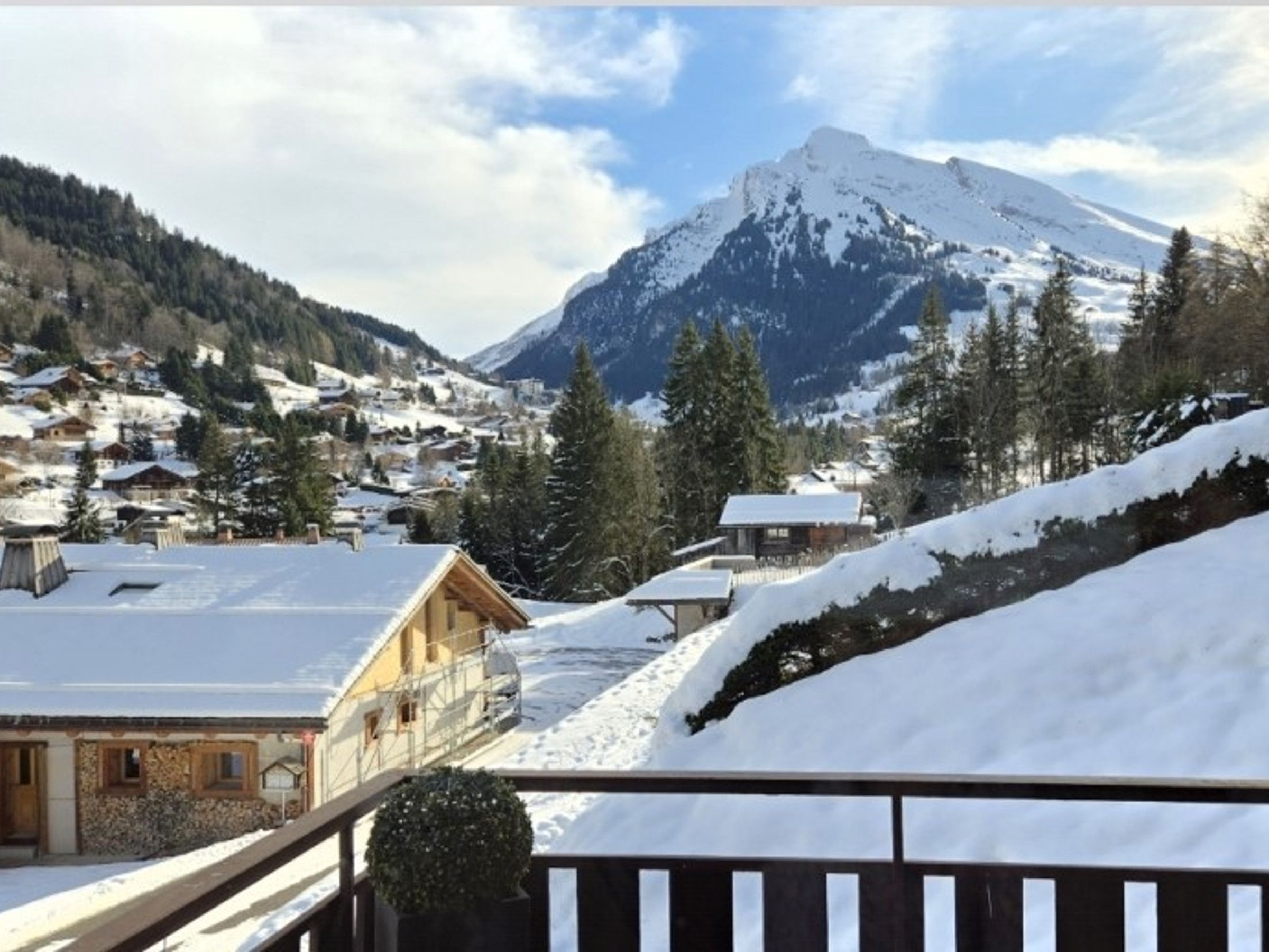 Eine verschneite Bergstadt mit Holzhäusern und einem markanten Berg im Hintergrund.