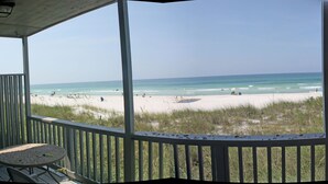 A beach view from a covered deck with a railing, a table, and chairs. - Exquisite 1st-Floor Panama City Beachfront, Low Density, Step from Deck to Sand  (Panama City Beach)