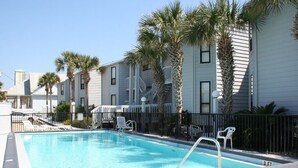 A swimming pool with a 3 FT depth marker, surrounded by a black fence, with palm trees and a building in the background. - Exquisite 1st-Floor Panama City Beachfront, Low Density, Step from Deck to Sand  (Panama City Beach)