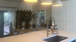 A kitchen with a large island, pendant lights, and a view of the backyard.