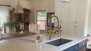 A kitchen with a large island, white cabinets, and pendant lighting.