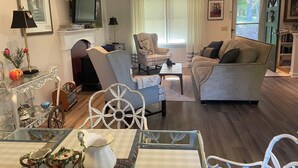 Ein Wohnzimmer mit Fernseher, zwei Sofas, einem Esstisch mit Stühlen und einem Kamin.