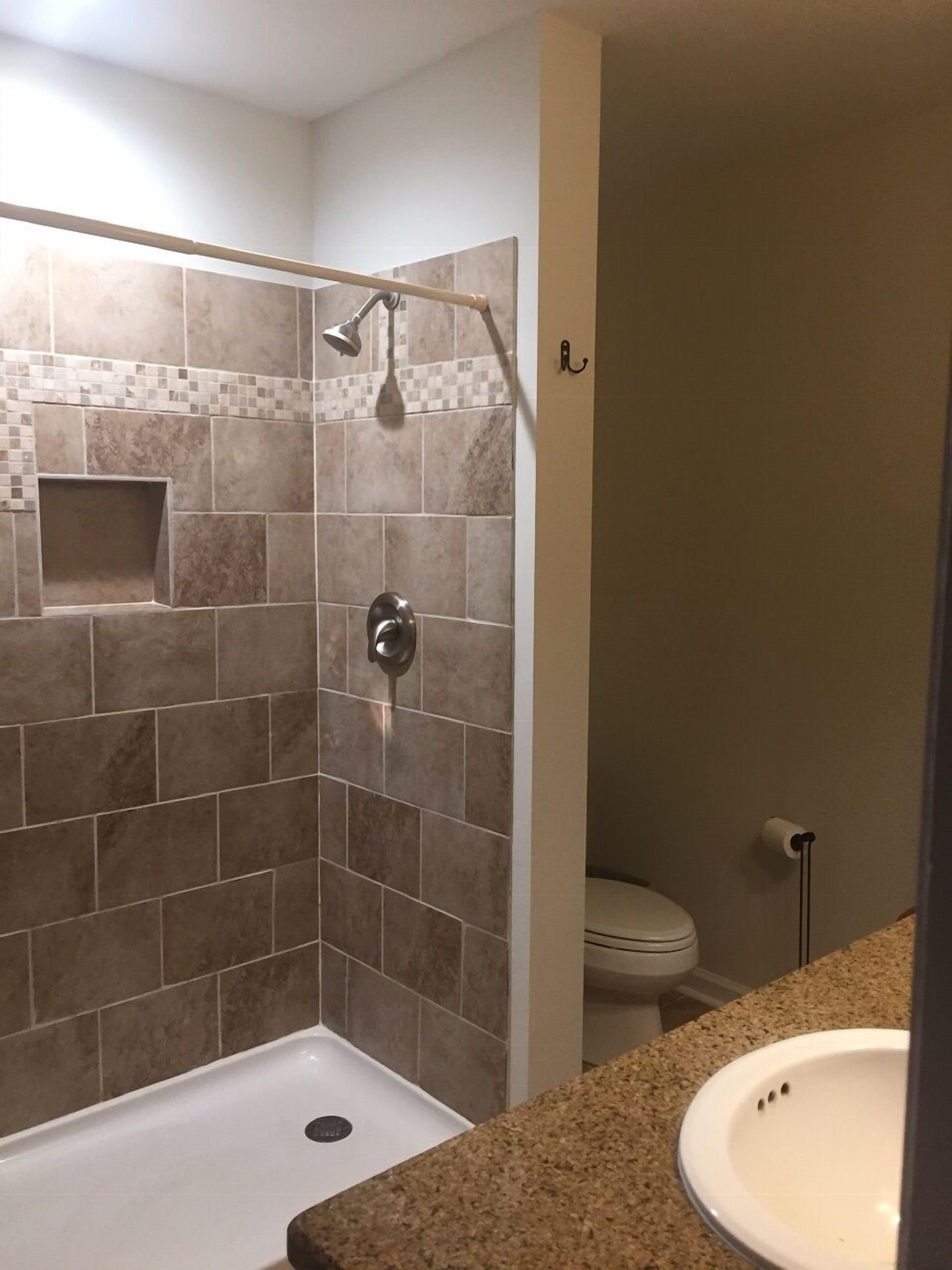 Master bath with vanity, lg. tiled shower, shelves with towels, hairdryer & more