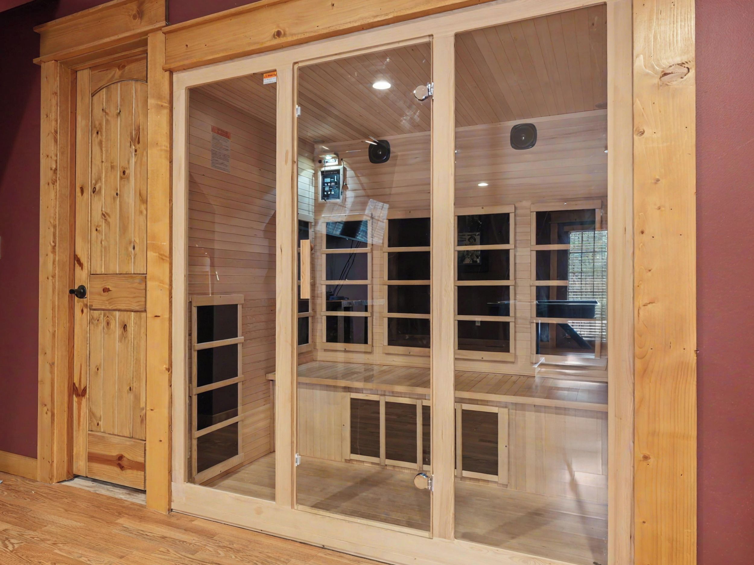 A wooden room with a sliding glass door, a ceiling-mounted light fixture, and a visible thermostat on the wall.