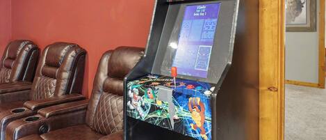 Una sala de juegos con videojuegos Multicade e iCade, sillones de cuero reclinables y un cuadro en la pared.