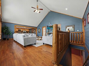 A spacious living area with a wooden ceiling, a dining table, and a kitchen in the background.