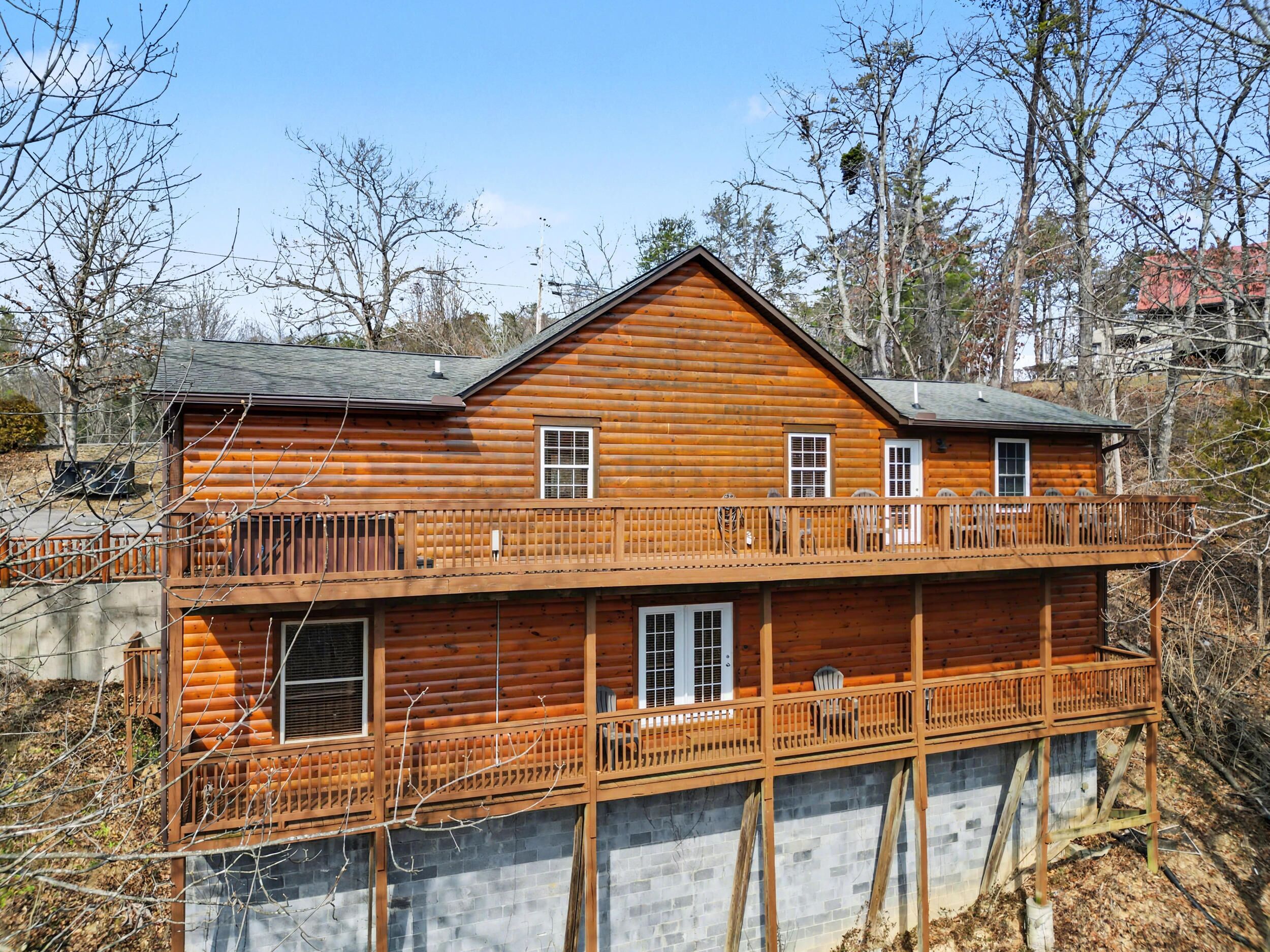 A two-story log cabin with a balcony and a stone foundation.