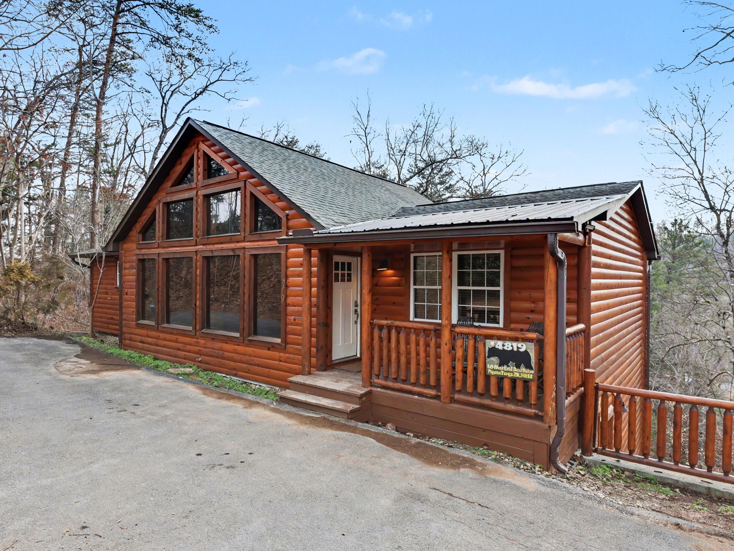 A wooden cabin with large windows, a porch, and a sign indicating it is a historic site.