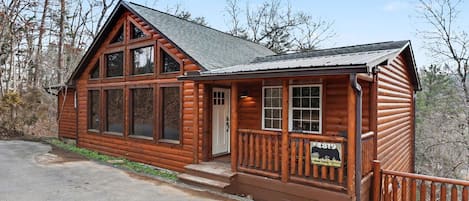 A wooden cabin with large windows, a porch, and a sign indicating it is a historic site.