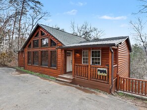 A wooden cabin with large windows, a porch, and a sign indicating it is a historic site.