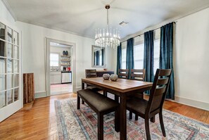 A dining room with a wooden table, dark chairs, a chandelier, and a patterned rug. - Lincoln Lodge A,near OU Med, Bricktown, Arena (Oklahoma City)
