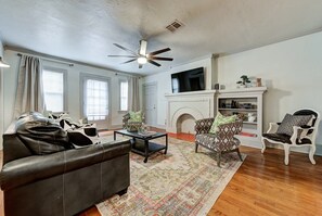 A living room with a fireplace, a ceiling fan, and a TV mounted above it. - Lincoln Lodge A,near OU Med, Bricktown, Arena (Oklahoma City)