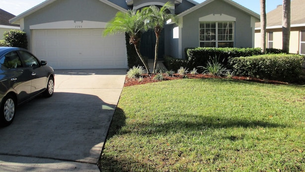 A residential house with a garage, a driveway, and a lawn. - Villa Bonita. Southern Dunes 4 star golf course. Disney and Legoland area. (Haines City)