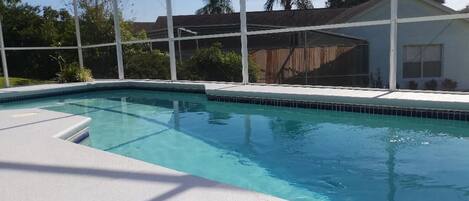 Piscina com deck branco e área coberta.