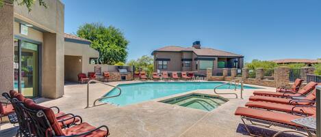 A pool area with lounge chairs and a building in the background.
