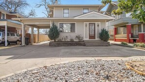 A two-story house with a covered driveway and a gravel front yard.