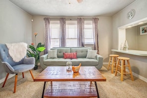 Ein Wohnzimmer mit einer Couch, einem Sessel, einem Couchtisch und einer Bar mit Sitzgelegenheiten.