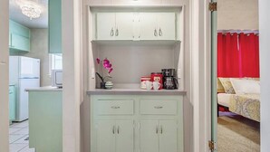 A kitchenette with a refrigerator, microwave, and a small countertop with a vase of flowers.