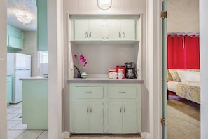 A kitchenette with a refrigerator, microwave, and a small countertop with a vase of flowers.