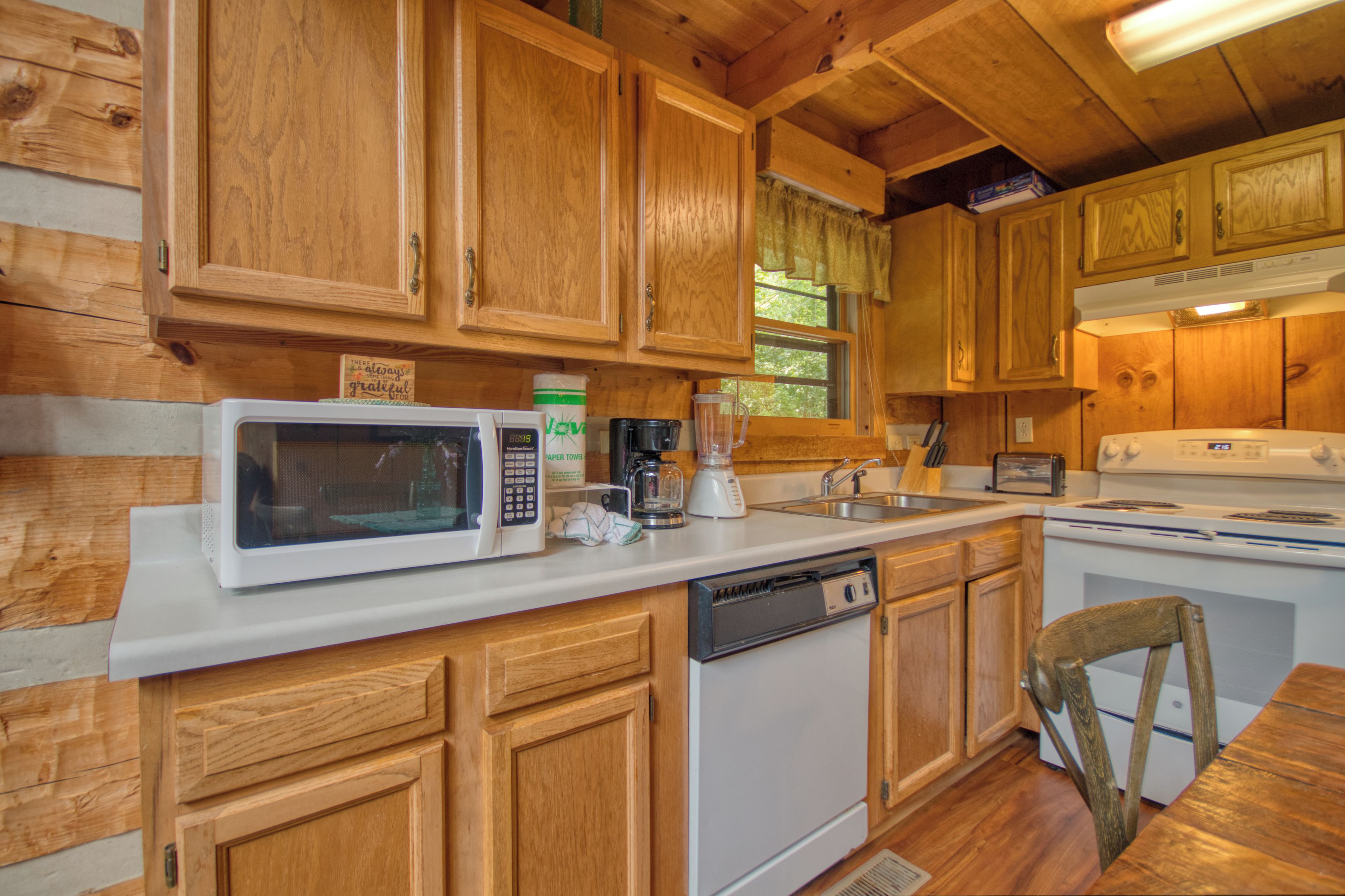 Una cocina de estilo cabaña de madera con microondas, cafetera y lavavajillas.