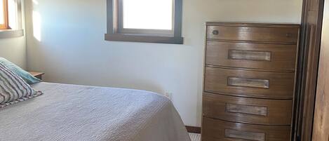 A bedroom with a bed, a dresser, a ceiling fan, a window with blinds, and a rug.