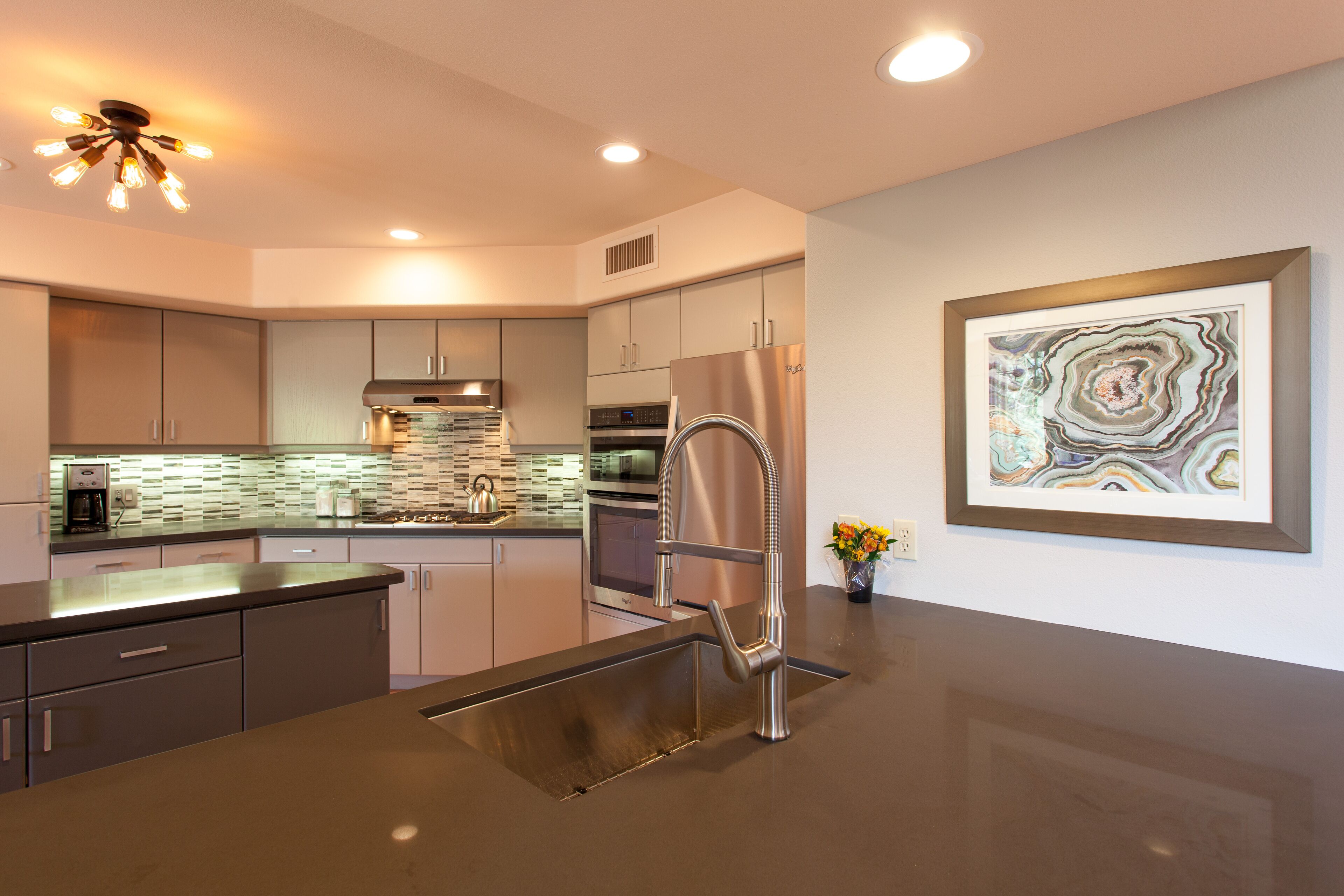A modern kitchen with stainless steel appliances, a built-in oven, and a unique backsplash.