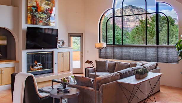 Un salon moderne doté d’une cheminée, d’un grand téléviseur et d’un coin salon confortable offrant une vue sur un paysage montagneux grâce à une grande fenêtre.
