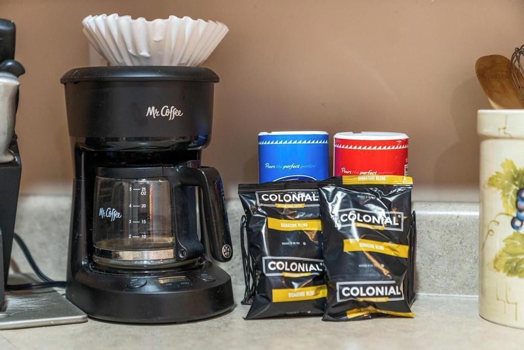 A coffee maker, two coffee pods, and a mug on a kitchen counter.
