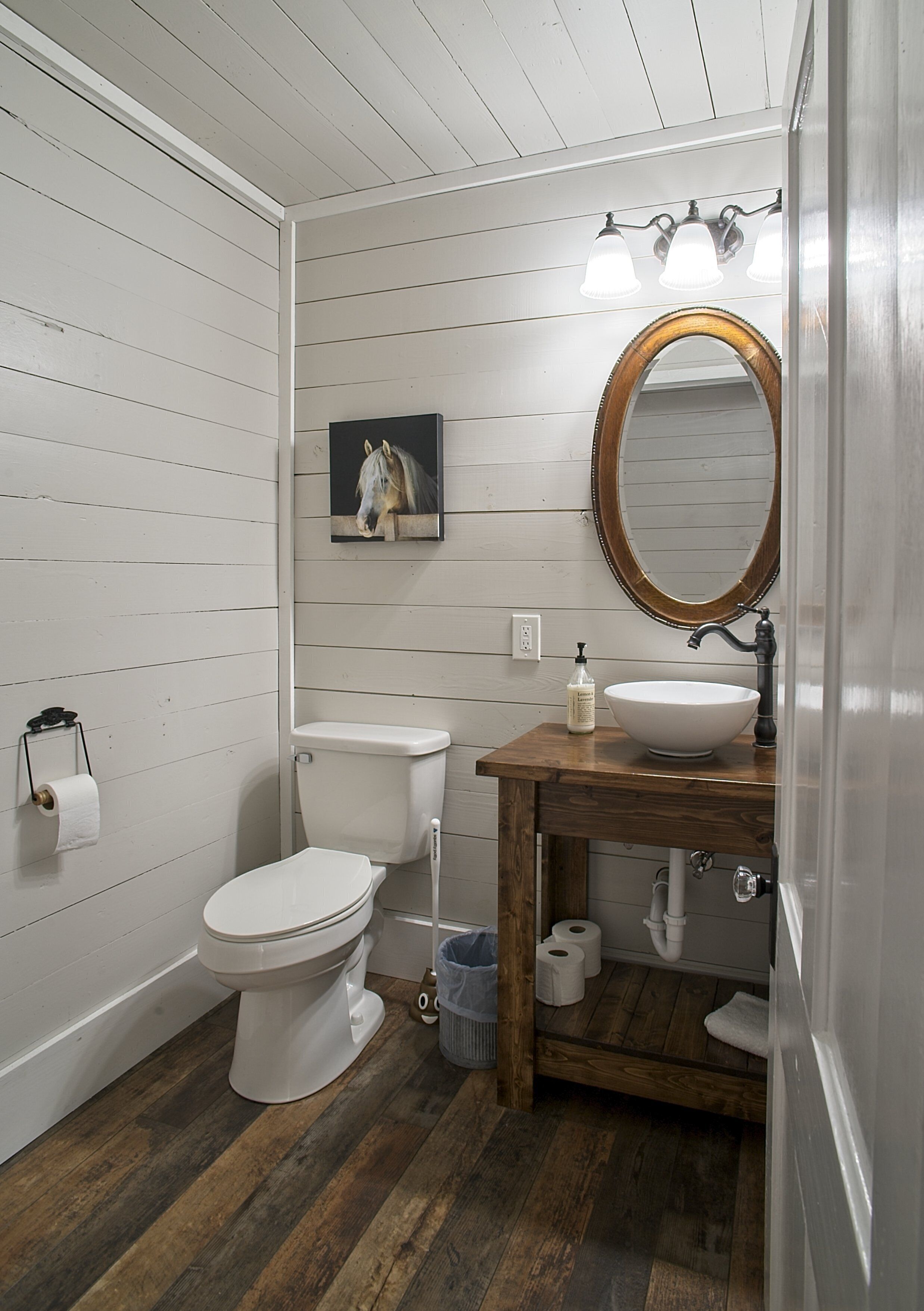 Ein Badezimmer mit einem Holzkosmetikschrank, einer weißen Toilette und Holzboden.