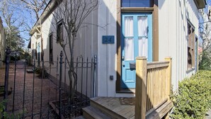 Une maison traditionnelle avec une porte bleue, le numéro 24, et un porche avant en bois.