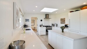 A modern kitchen with white cabinetry, a central island, and a built-in oven.