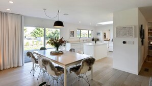 A modern kitchen with white cabinetry, a central island, and a dining area with fur-covered chairs.