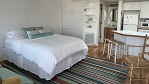 A bedroom with a bed, a small desk, and a chair. There is a kitchenette with a refrigerator and microwave. - Prime location and the perfect getaway for two (Wrightsville Beach)
