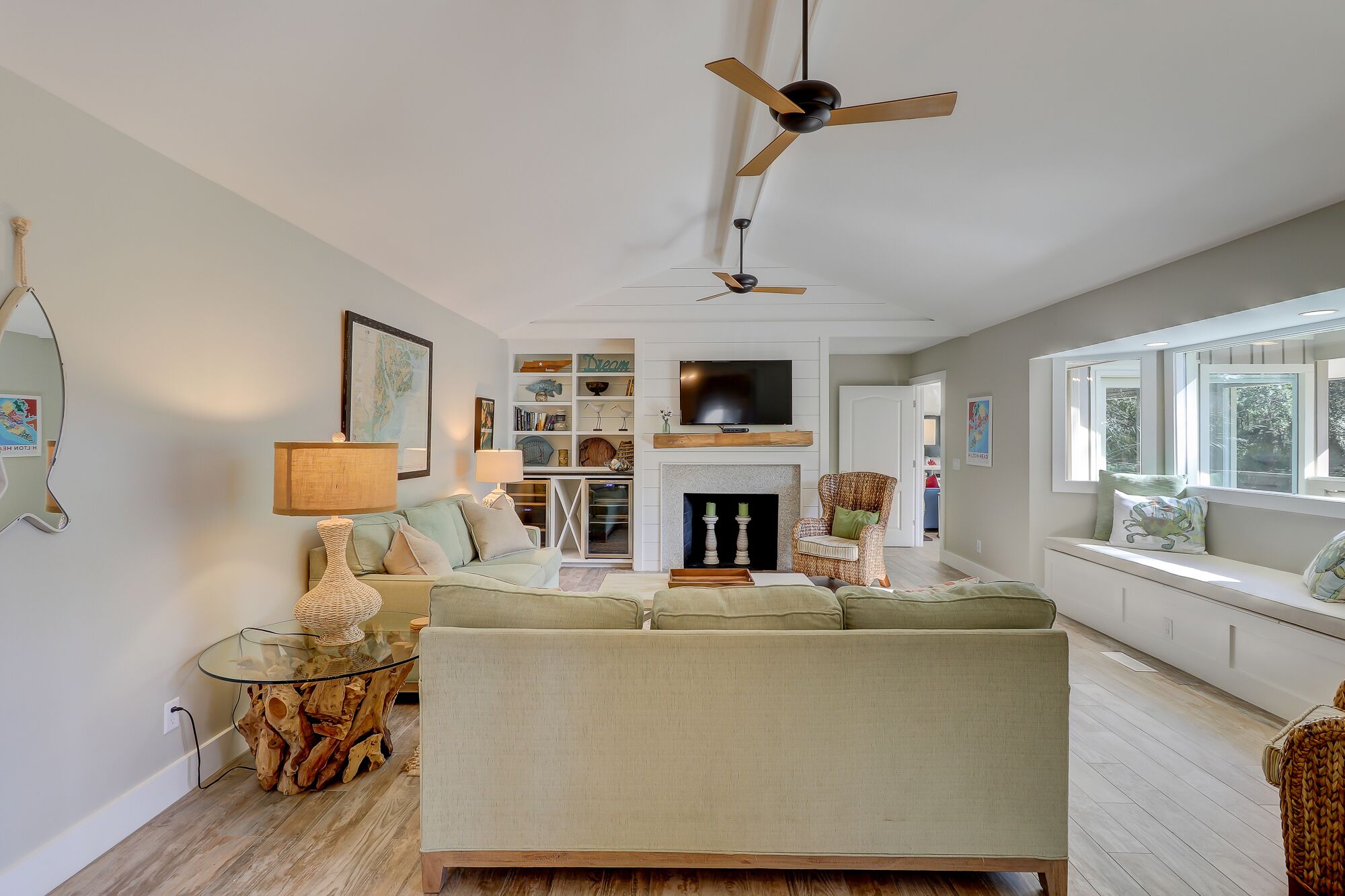 A spacious living room with a sofa, a coffee table, a fireplace, and a television mounted on the wall.