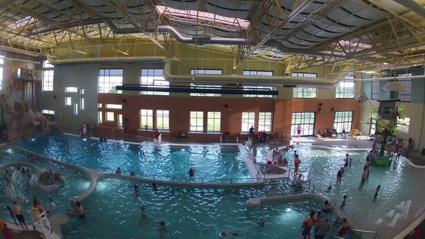 Una piscina interior amb diverses línies de bades, un tobogan d'aigua i una zona de jocs.
