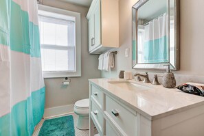 A bathroom with a white sink, a mirror, a toilet, and a shower curtain.
