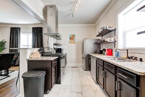 A modern kitchen with a central island, stainless steel appliances, and a window with curtains.