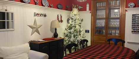 Un comedor acogedor con mantel a cuadros, un sofá blanco y un árbol de Navidad.