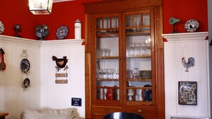 A room with a red wall, a wooden cabinet with glass doors, and various decorative plates and signs. - LA VIE EST BELLE - 4+1BEDroom -  Free Parking - A/C  (Montréal)