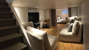 A modern living room with a staircase, a flat-screen TV, a sofa, and a bed in the background. - LA VIE EST BELLE - 4+1BEDroom -  Free Parking - A/C  (Montréal)
