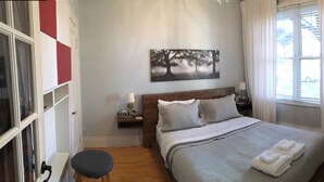 A bedroom with a bed, a nightstand, a chair, a window with curtains, and a wall-mounted picture. - LA VIE EST BELLE - 4+1BEDroom -  Free Parking - A/C  (Montréal)