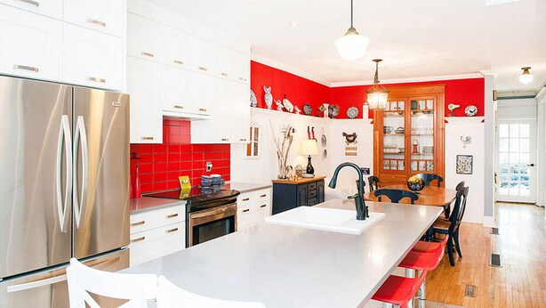 A modern kitchen with white cabinets, a stainless steel refrigerator, a red backsplash, and a central island with bar seating. - LA VIE EST BELLE - 4+1BEDroom -  Free Parking - A/C  (Montréal)