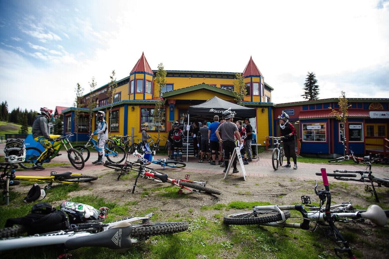 Um edifício com fachada amarela e telhados vermelhos, cercado por bicicletas e pessoas.