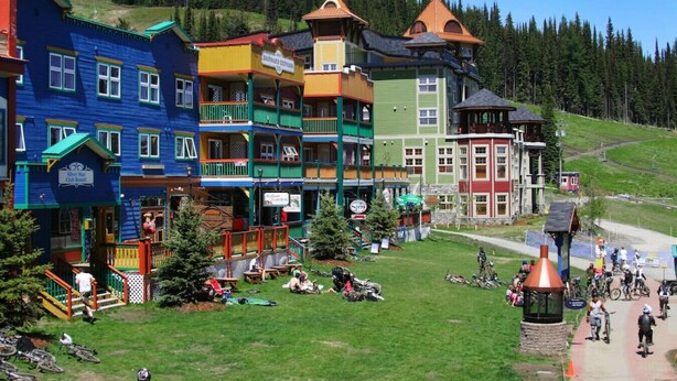 Edifícios coloridos com varandas e uma pista de esqui ao fundo.